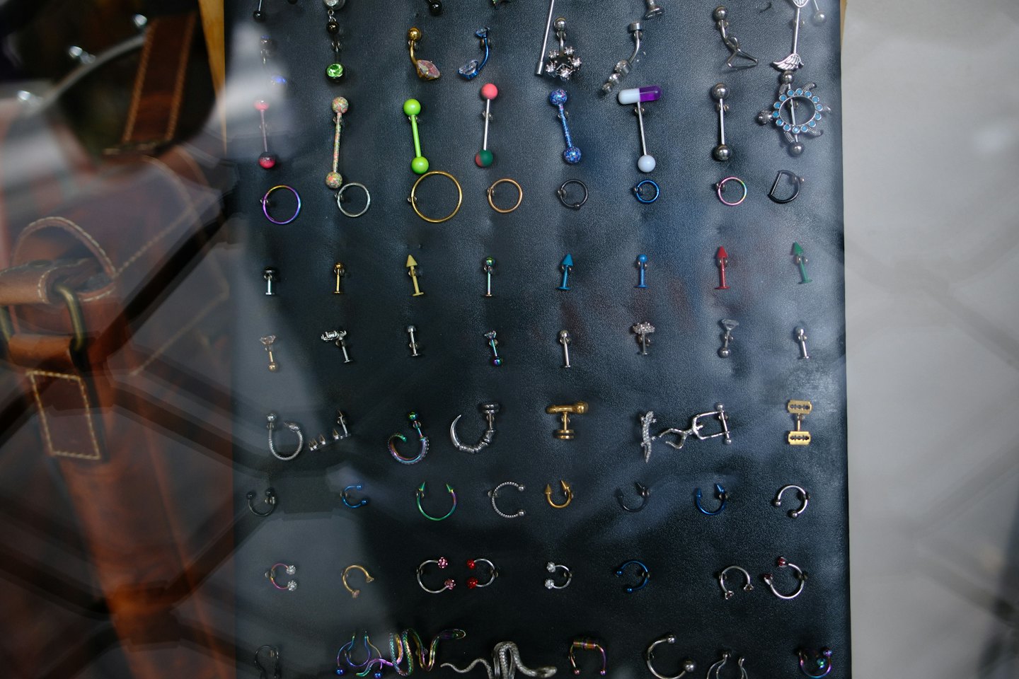 Metallic body piercings arranged on a black display board.